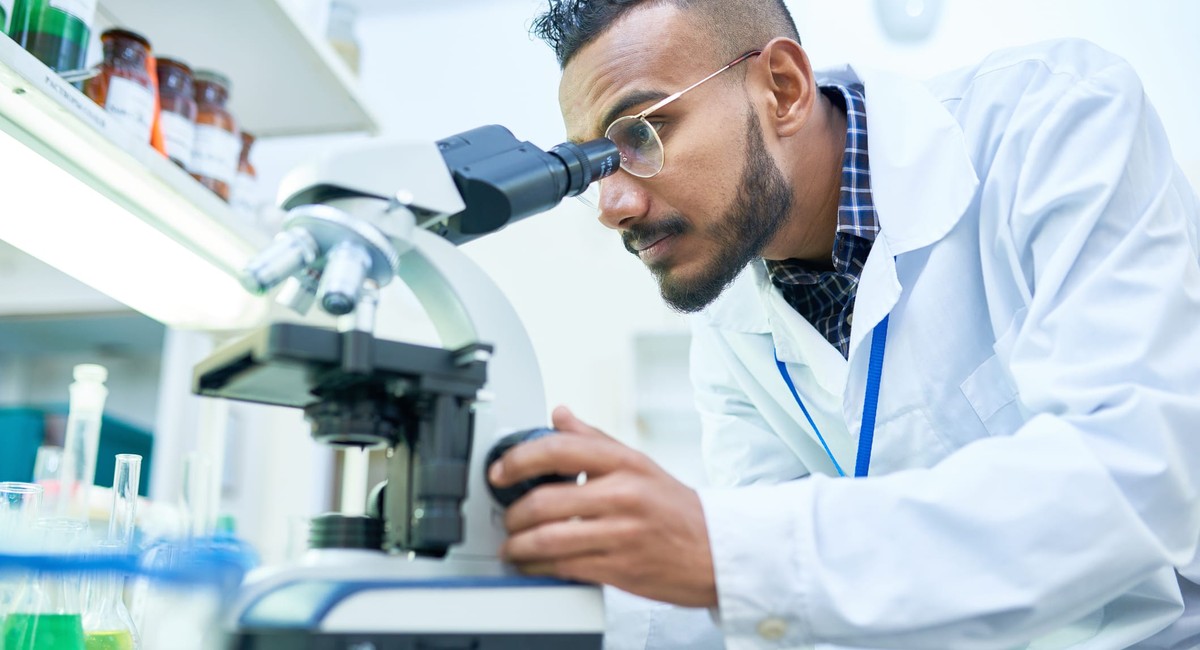 Biotech researcher looking through a microscope in a life sciences laboratory